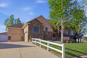 View of front of property with stone siding, stucco siding, concrete driveway, and an attached garage