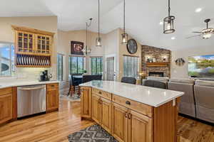 Kitchen featuring dishwasher, glass fronted cabinets, a fireplace, a kitchen island, and light wood finished floors