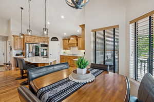 Dining area featuring lofted ceiling, light wood finished floors, and suspended lighting
