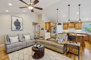 Living room with light wood-style flooring, a ceiling fan, recessed lighting, and vaulted ceiling