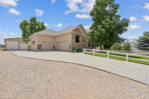 View of front of property with stone siding, driveway, stucco siding, and an attached garage