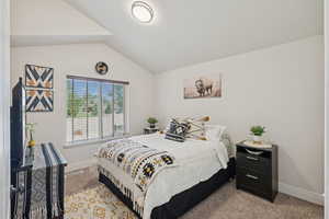 Bedroom featuring light colored carpet and lofted ceiling