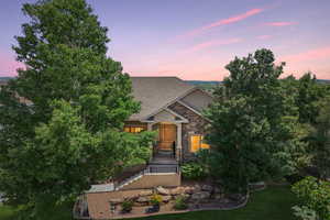View of front of house featuring stone siding, roof with shingles, stucco siding, and a yard
