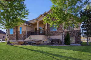 View of front of house featuring stone siding, stucco siding, and a front lawn