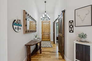 Entryway with a barn door, suspended lighting, and wood finished floors