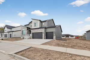 View of front of property featuring stone siding, driveway, a garage, and a residential view