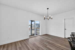 Unfurnished dining area with dark wood-style floors, hanging lights, and a textured ceiling