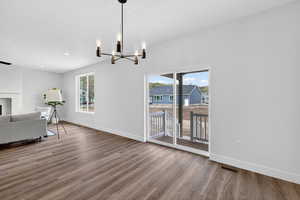 Dining space with plenty of natural light, a fireplace, dark wood-style floors, and a chandelier