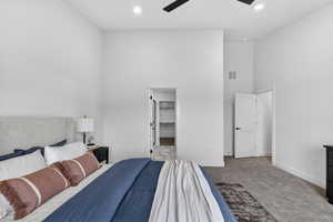 Carpeted bedroom with a high ceiling, a walk in closet, recessed lighting, and ceiling fan