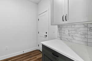Laundry room with baseboards and dark wood finished floors