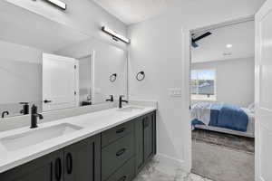 Ensuite bathroom with double vanity, light marble finish floors, and a textured ceiling