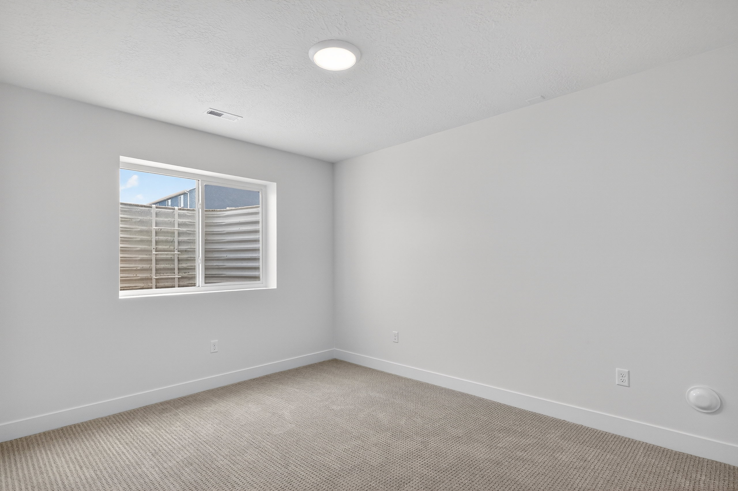 Empty room with light carpet and a textured ceiling