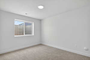 Empty room with light carpet and a textured ceiling