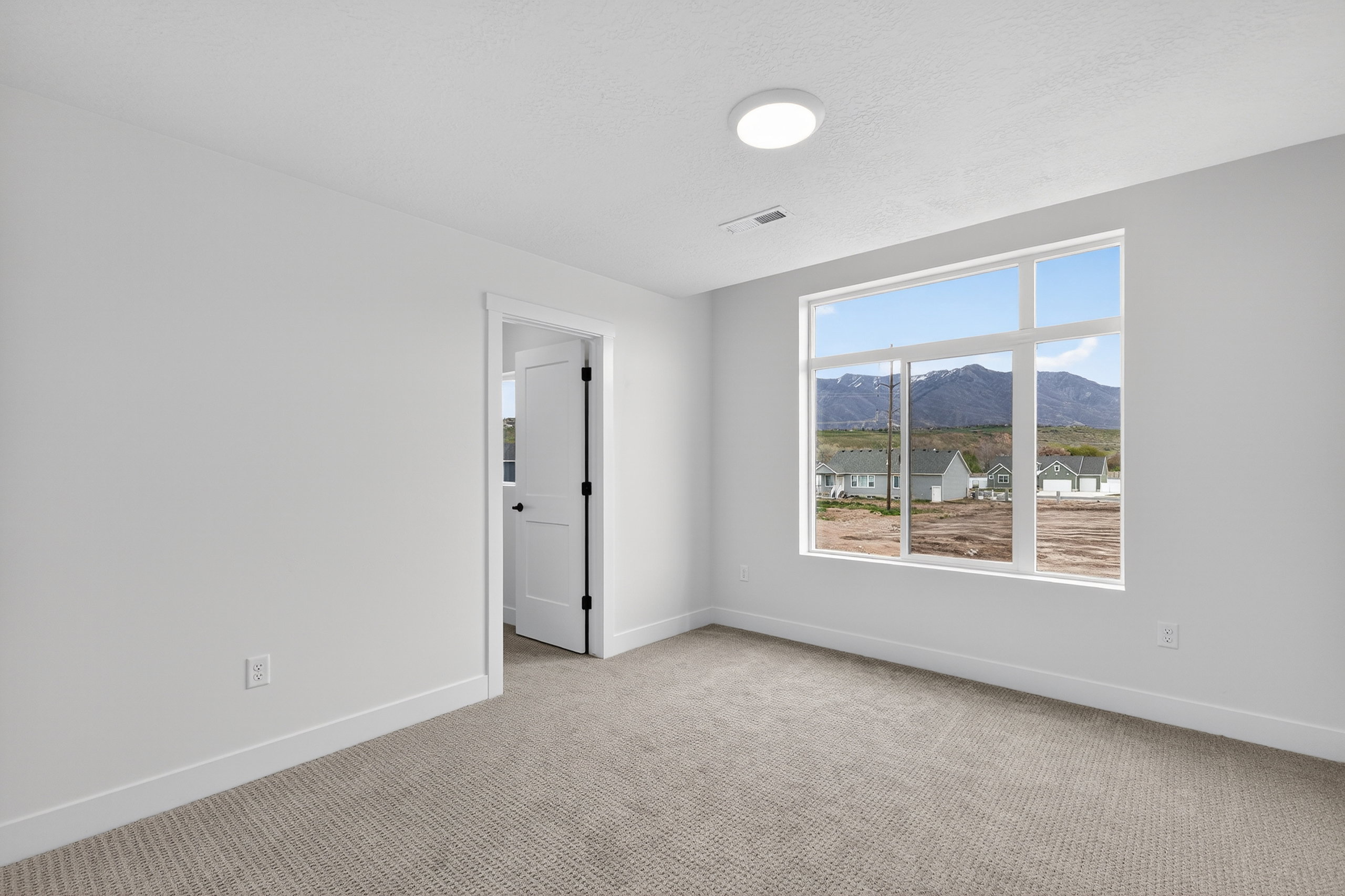 Empty room featuring a mountain view and light carpet