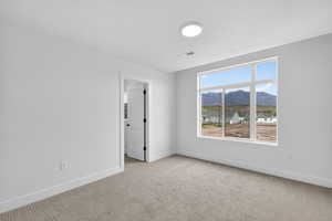 Empty room featuring a mountain view and light carpet