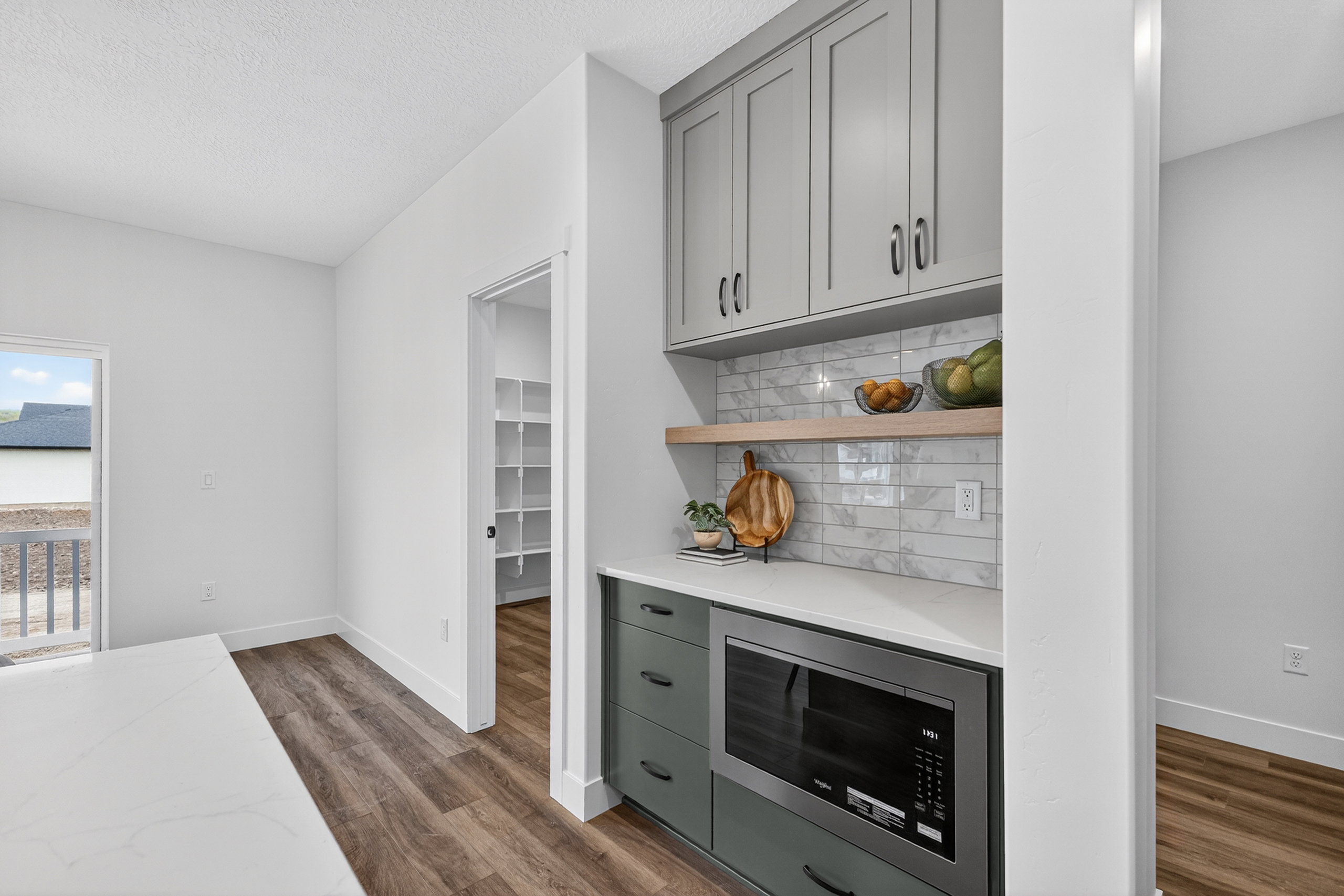 Bar area with stainless steel microwave, open shelves, gray cabinets, dark wood finished floors, and light stone counters