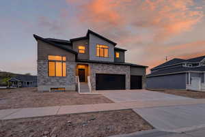 Modern home with stone siding, concrete driveway, and a garage