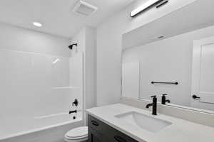 Bathroom with vanity, bathing tub / shower combination, and a textured ceiling