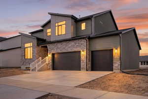 Modern home with stone siding, driveway, and a garage