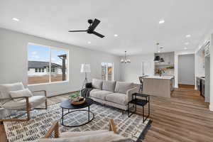 Living area with hanging lights, ceiling fan, light wood-style flooring, and healthy amount of natural light