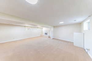 Basement with a brick fireplace, light carpet, and healthy amount of natural light