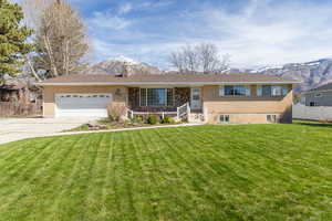 View of front of property with a mountain view, an attached garage, a chimney, and brick siding