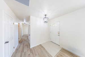Entryway featuring light wood-style floors and suspended lighting