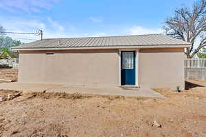 Back of house featuring stucco siding and a metal roof