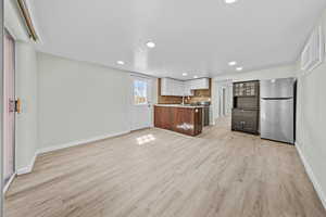 Kitchen with open floor plan, freestanding refrigerator, recessed lighting, glass insert cabinets, and tasteful backsplash