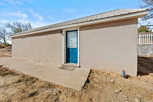 View of exterior entry featuring stucco siding and a metal roof
