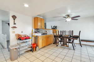 Kitchen with light countertops, ceiling fan, light tile patterned flooring, and wood finish cabinetry