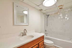 Bathroom featuring vanity, a drop ceiling, and bathing tub / shower combination