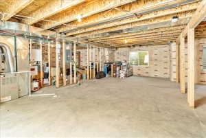 Unfinished basement featuring a concrete floor, exposed wood framing, and multiple utility windows
