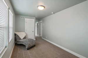 Living area with dark colored carpet and a textured ceiling