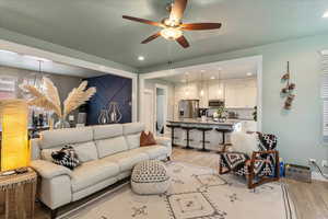 Living area with a ceiling fan, light wood-style floors, and recessed lighting