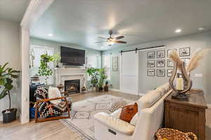 Living area featuring a barn door, wood finished floors, a ceiling fan, a textured ceiling, and recessed lighting