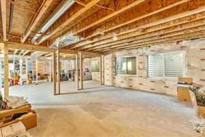 Unfinished basement featuring exposed wood joists, concrete flooring, framing for multiple rooms, and two egress windows