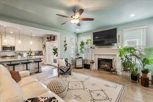 Living area featuring light wood-style floors, recessed lighting, a textured ceiling, a ceiling fan, and a glass covered fireplace