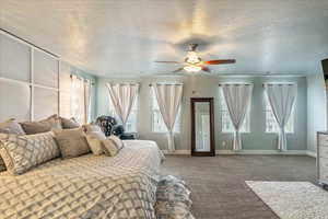 Bedroom featuring dark colored carpet, a textured ceiling, and ceiling fan