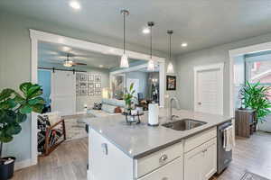 Kitchen with a center island with sink, a barn door, light wood-style floors, white cabinetry, and open floor plan