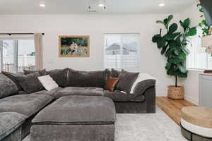Living room with plenty of natural light, wood finished floors, and recessed lighting