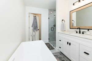 Bathroom featuring a soaking tub, vanity, and a shower