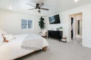 Primary Bedroom with a spacious closet, light carpet and ceiling fan.
