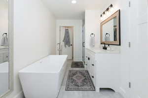 Primary suite bathroom featuring vanity, a freestanding bath, and light tile patterned floors