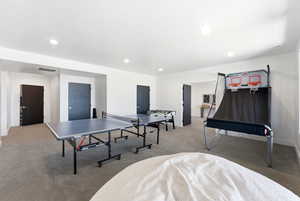 Recreation room with light colored carpet and recessed lighting