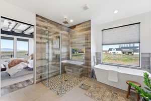 Ensuite bathroom with a freestanding tub, a stall shower, recessed lighting, light tile patterned floors, and tile walls