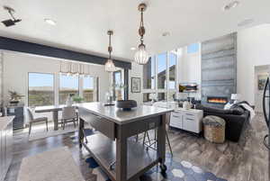 Kitchen featuring a large fireplace, dark wood-type flooring, plenty of natural light, and decorative light fixtures