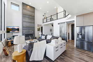 Living room featuring a barn door, a large fireplace, dark wood-type flooring, recessed lighting, and a high ceiling