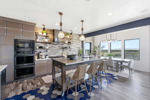 Kitchen featuring open shelves, double oven, decorative light fixtures, modern cabinets, and black microwave