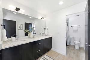 Bathroom with double vanity, light wood-style flooring, a shower with shower curtain, and recessed lighting